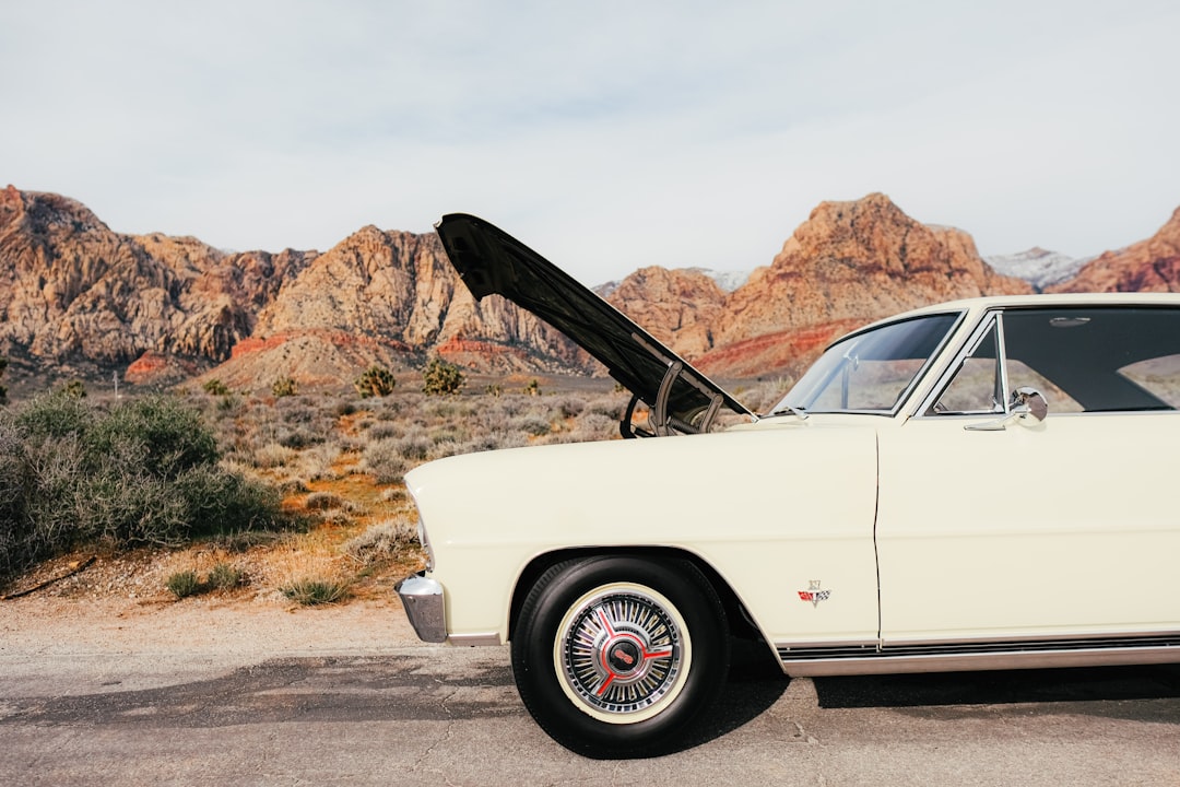 Classic car with open hood in desert landscape.