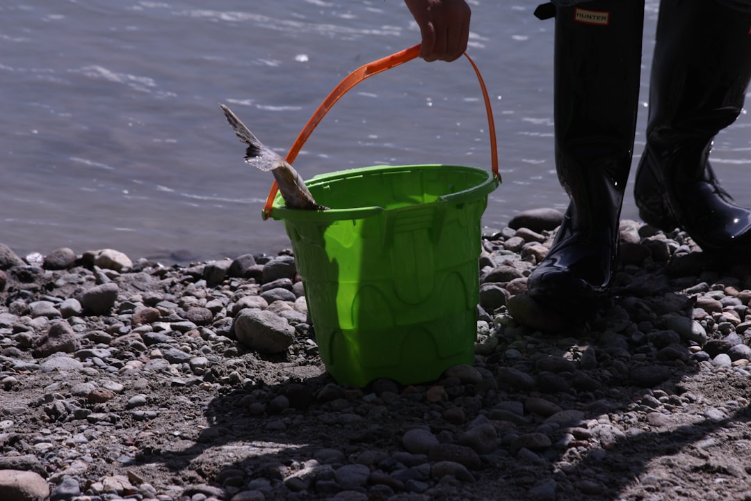 a person standing next to a green bucket