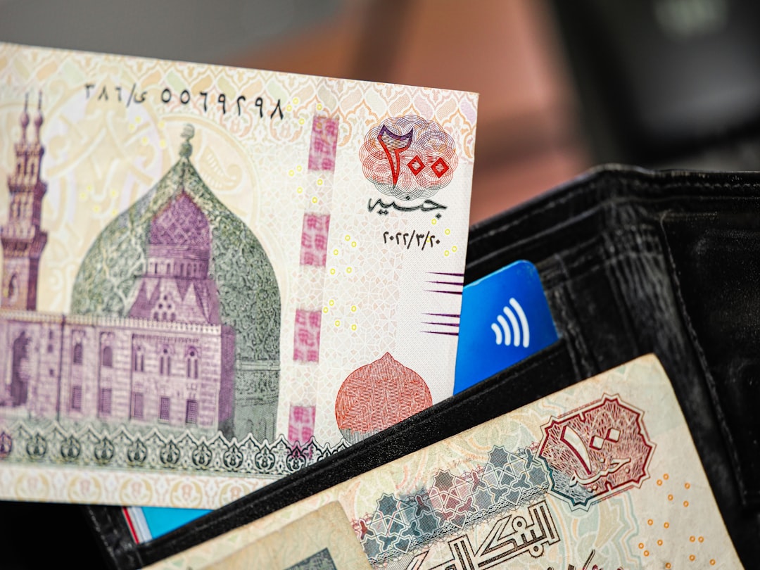 A person holding a wallet with a bank note sticking out of it
