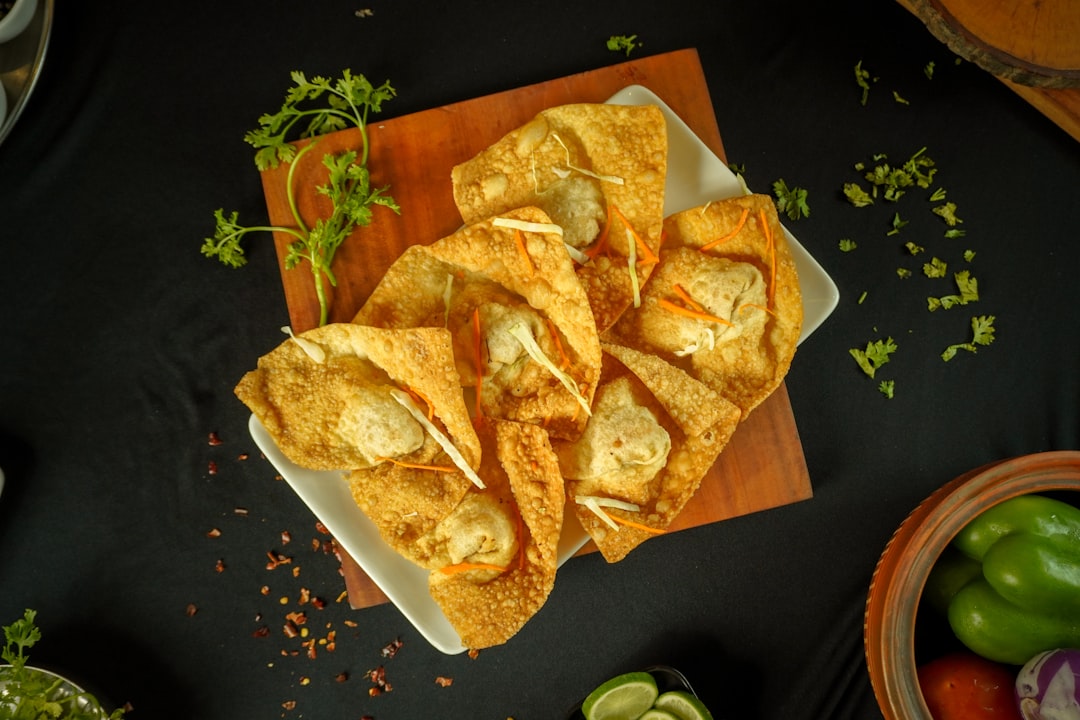Crispy fried wontons garnished with herbs on a dark background.