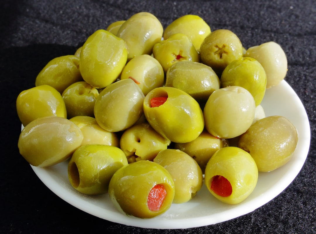 a white plate filled with green olives on a table
